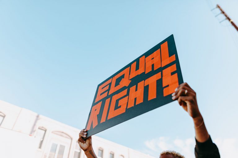 Hands raising a protest sign that reads Equal Rights