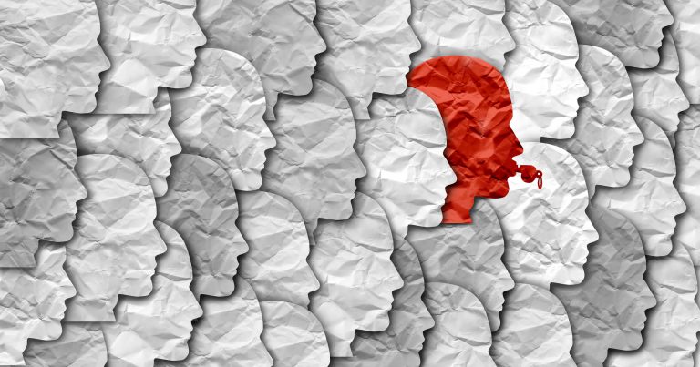 A single red crumpled paper standing out among grey crumpled papers